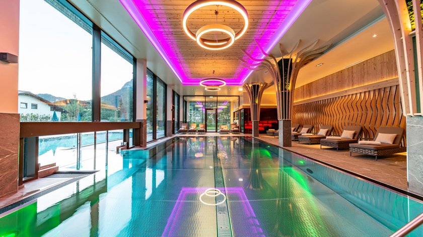 Die Vorteile von Aqua Yoga im Postwirt Moderner Innenpool mit Lounge-Stühlen und neonbeleuchtetem Deckenrahmen