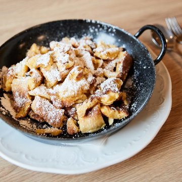 Holiday in Soll with children or as a couple Kaiserschmarrn in pan topped with powdered sugar on white plate
