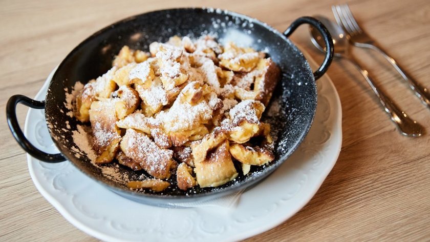 Tyrolean Kaiser-Schmarren Kaiserschmarrn in pan topped with powdered sugar on white plate