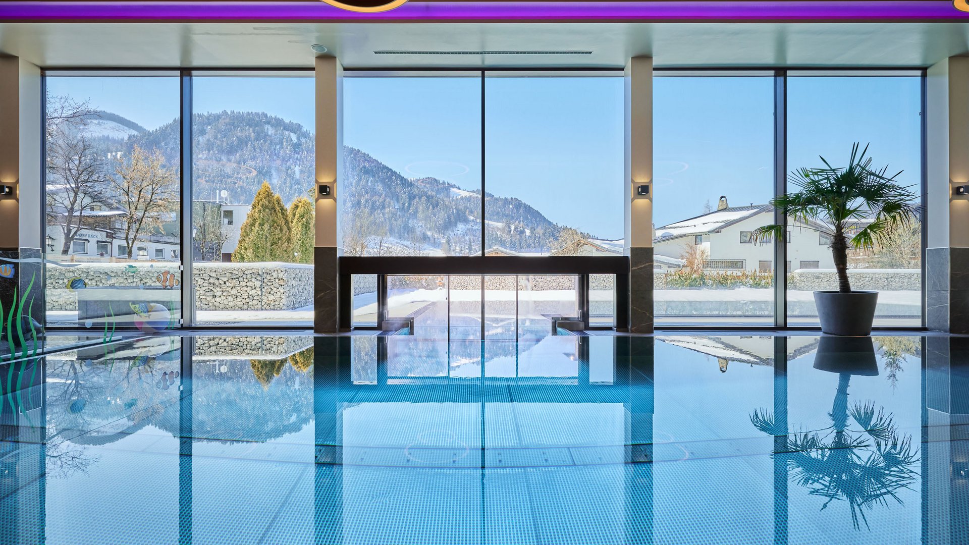 Ihre Traumtage im Postwirt Söll Innenpool mit großen Fenstern und Bergblick im Winter