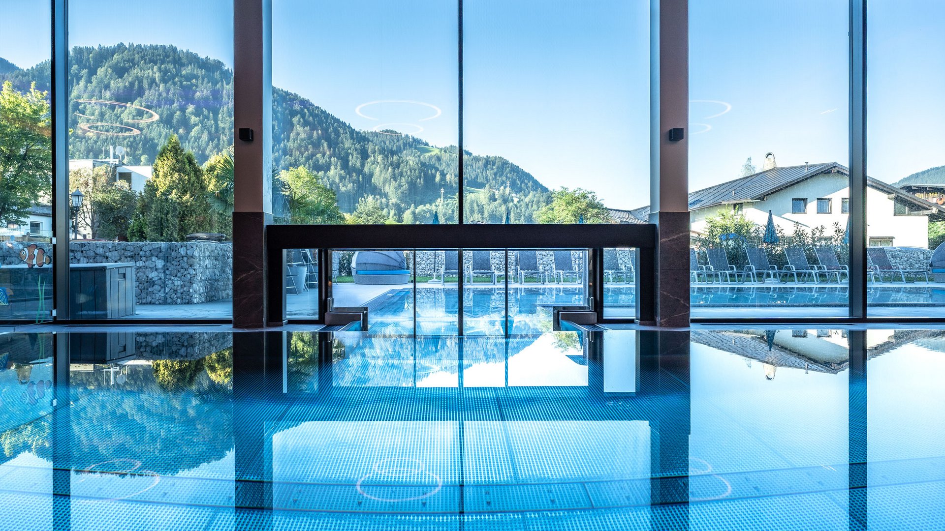 Indoor and outdoor pool with mountain view through large windows
