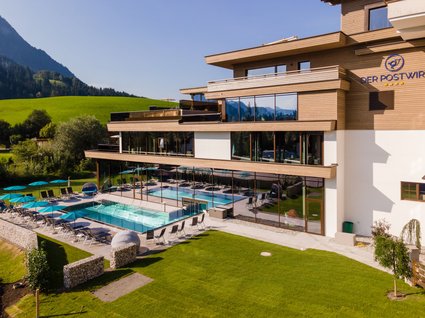 Day Spa in Söll: Kurzurlaub in Tirol Hotel mit Außenpool, Liegestühlen und Berglandschaft im Hintergrund