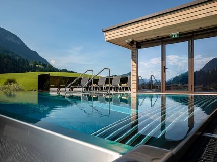 Kurzurlaub am Wilden Kaiser: Auszeit im Hotel Postwirt in Söll Moderner Außenpool mit Liegestühlen vor Berglandschaft und Sauna