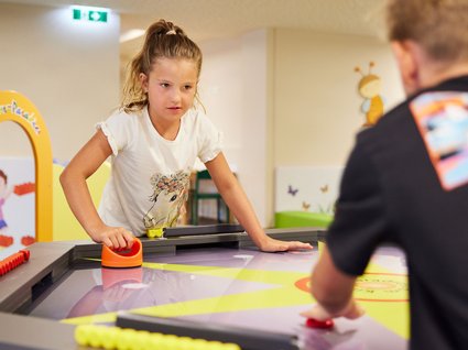 Fun and games in our family-friendly hotel in Soll Girl and boy playing a fun table game in colorful kids' play area