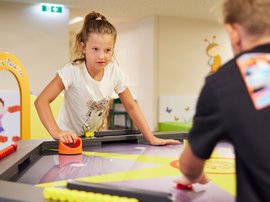 Hotel in Söll: the Postwirt Girl and boy playing a fun table game in colorful kids' play area