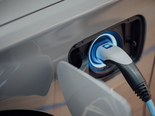 Unser Hotel in Söll/Österreich: eine spannende Geschichte Elektroauto wird mit Stecker an Ladeanschluss geladen