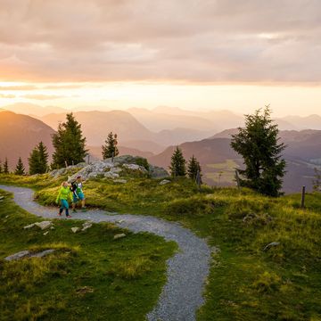 Urlaub in Söll mit Kindern oder als Pärchen Zwei Wanderer auf einem Pfad bei Sonnenuntergang in den Bergen
