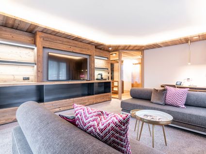 Kurzurlaub am Wilden Kaiser: Auszeit im Hotel Postwirt in Söll Modernes Wohnzimmer mit grauen Sofas und Fernseher in Holzwand