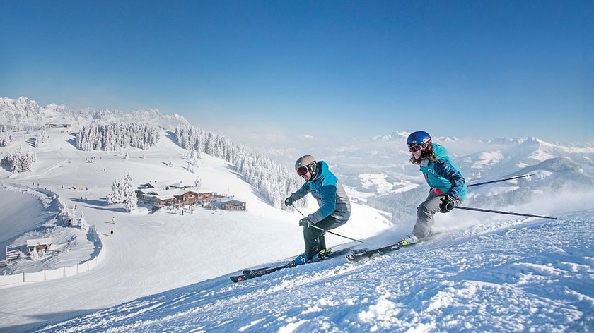 Aktiv das neue Jahr beginnen Zwei Skifahrer fahren auf verschneiter Skipiste bei klarem Himmel