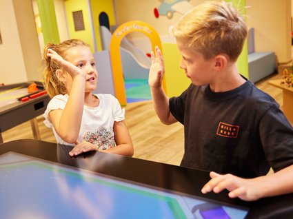 Fun and games in our family-friendly hotel in Soll Two children giving each other a high-five in a playroom