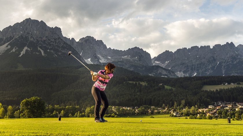 Ein kaiserlicher Sommer Frau spielt Golf vor einer Berglandschaft mit bewölktem Himmel