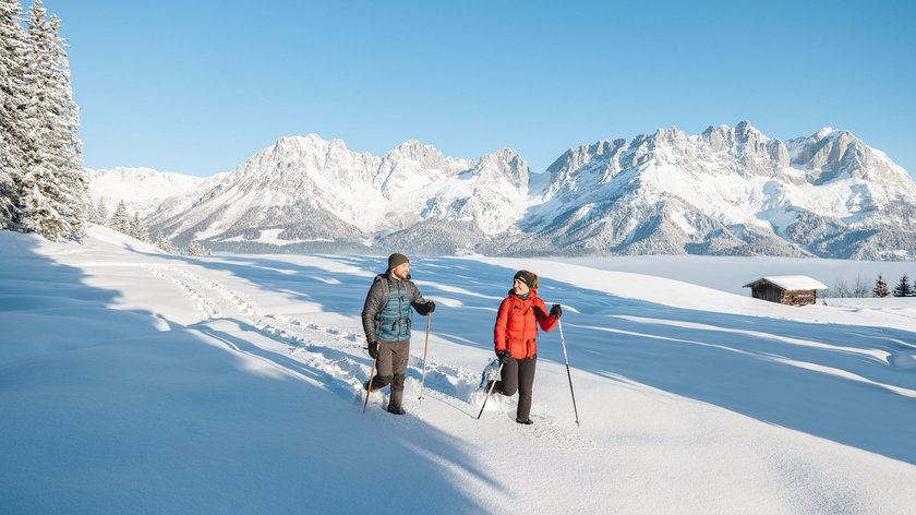 Hinauf zu Hollenauer Kreuz Zwei Personen bei Winterwanderung im Schnee vor verschneiten Bergen und blauem Himmel