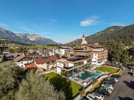 Hotel in Söll: the Postwirt View of a hotel with pool in an alpine village surrounded by mountains and forest
