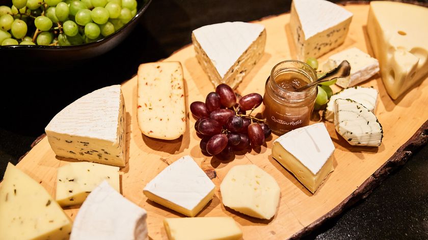 Herbsthighlights für Gourmets und Weinliebhaber Verschiedene Käsesorten mit rohen Trauben und Quitten-Apfel-Gelee auf Holzbrett