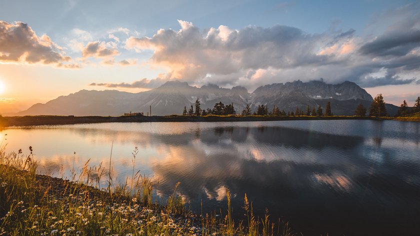 Nachhaltig die Natur im Mittelpunkt Berglandschaft mit See und Blumen im Vordergrund bei Sonnenuntergang