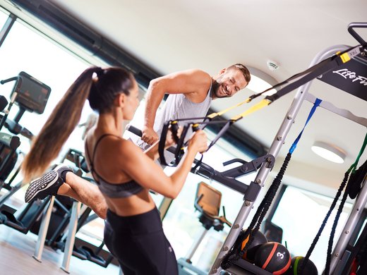 Sie suchen ein Hotel mit Fitnessstudio in Österreich? Mann und Frau trainieren mit TRX-Bändern im Fitnessstudio