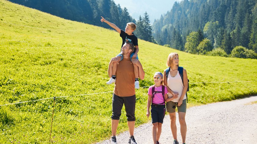 Sommerliche Familienabenteuer in Söll Familie wandert auf einem Weg in den Bergen an sonnigem Tag