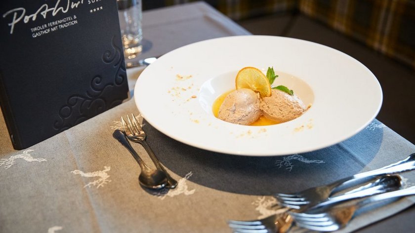 Chocolate & Mousse au Chocolat Dessert with two scoops of ice cream, orange slice, and mint on a white plate