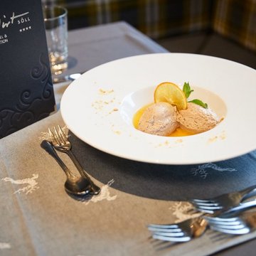 Holiday in Soll with children or as a couple Dessert with two scoops of ice cream, orange slice, and mint on a white plate