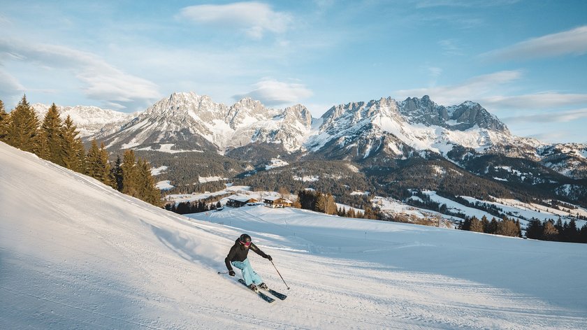 Erleben Sie den Winterzauber in Söll Skifahrer auf schneebedeckter Piste mit Bergpanorama und blauem Himmel
