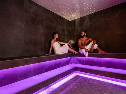 Dampfbad im Wellnessbereich mit stimmungsvoller Beleuchtung Couple relaxing in a sauna with purple lighting