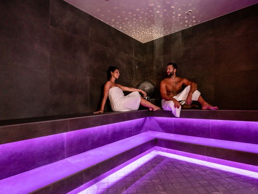 Wellness and spa hotel in Soll Couple relaxing in a sauna with purple lighting