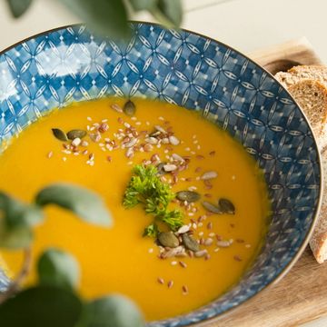 Urlaub in Söll mit Kindern oder als Pärchen Orangefarbene Suppe mit grüner Garnitur und Saaten, dazu Scheiben Brot