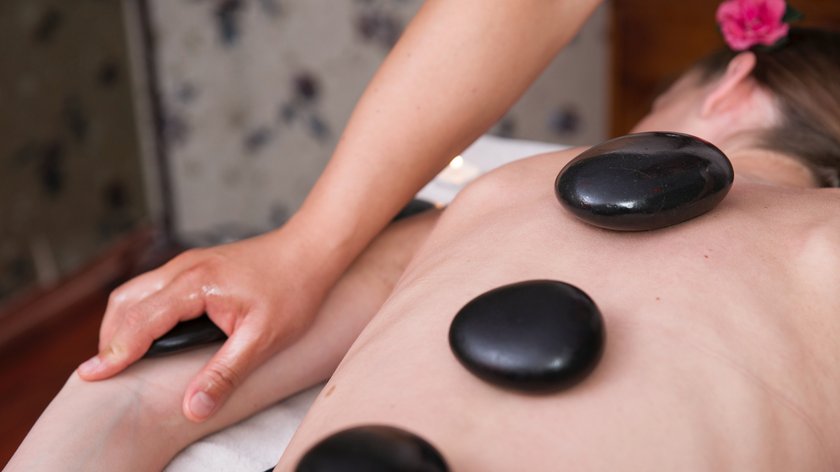 Die Hot-Stone-Massage Person erhält Hot-Stone-Massage mit Steinen auf dem Rücken und Arm-Massage