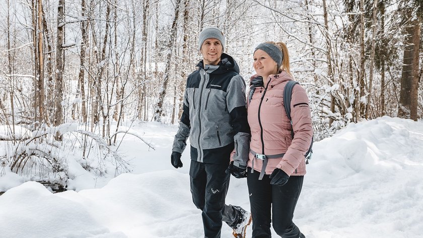 Winterwandern am Wilden Kaiser: die Biedringer Platte Paar wandert im Schnee bei winterlichem Waldspaziergang