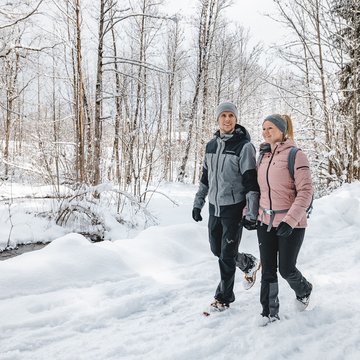 Urlaub in Söll mit Kindern oder als Pärchen Paar wandert im Schnee bei winterlichem Waldspaziergang