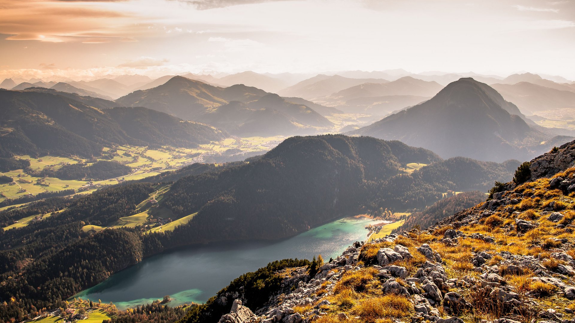 Discover the benefits of the Wilder Kaiser GästeCard to be used in your holiday area- Autumn mountain landscape with lake and rocky foreground in warm light