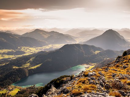 Discover the benefits of the Wilder Kaiser GästeCard to be used in your holiday area- Autumn mountain landscape with lake and rocky foreground in warm light