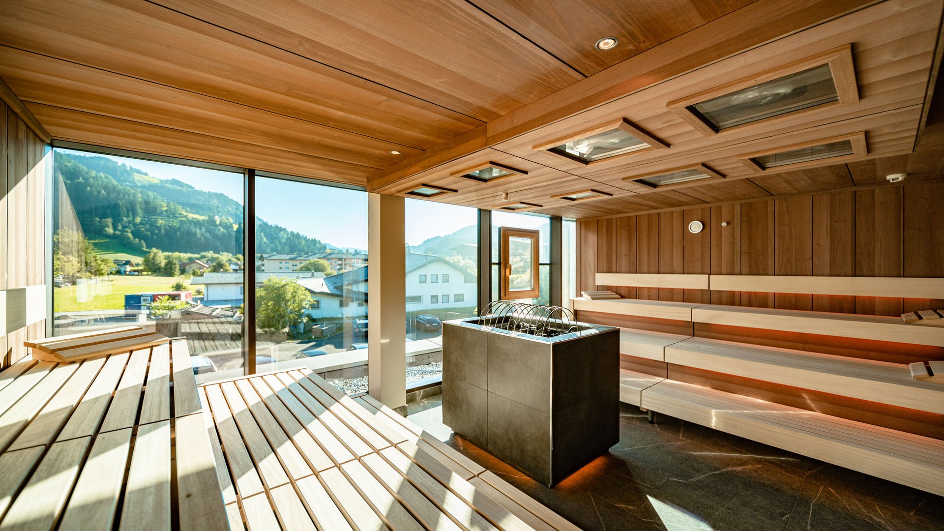 Holidays at the Postwirt: more than just in “a” hotel in Soll. Modern sauna interior with wooden panels and mountain view through large windows