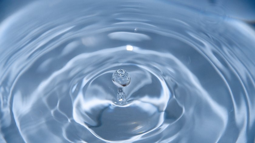 Erleben Sie Ihr blaues Wunder. Wassertropfen erzeugt Kreise auf Wasseroberfläche