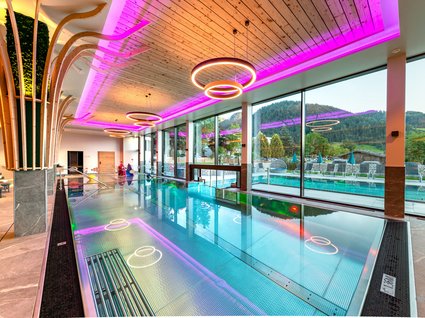 Holidays at the Postwirt: more than just in “a” hotel in Soll. Modern indoor pool with large glass wall and purple ceiling lights