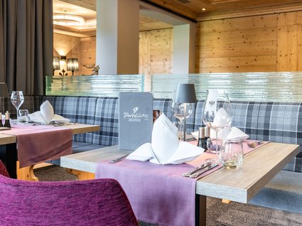 Holidays at the Postwirt: more than just in “a” hotel in Soll. Elegant set table in modern restaurant with plaid upholstered bench seating