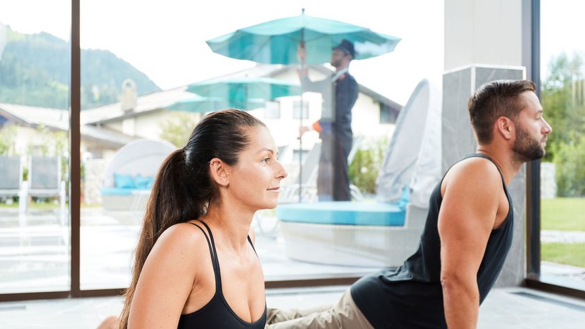 Aktive Erholung im Frühling Mann und Frau machen Yoga-Übungen auf Matten in einem hellen Raum mit Aussicht