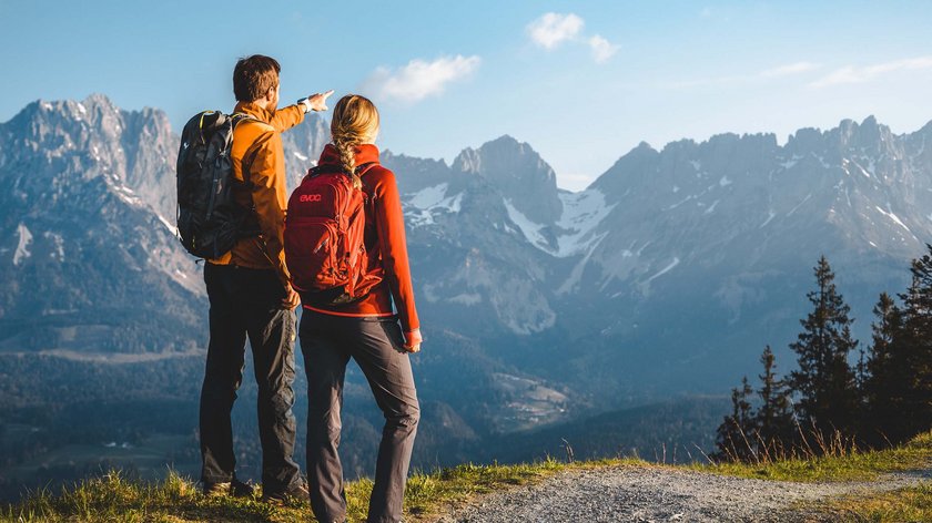 Frühlingswanderungen am Wilden Kaiser Zwei Wanderer stehen auf einem Pfad und blicken auf schneebedeckte Berggipfel