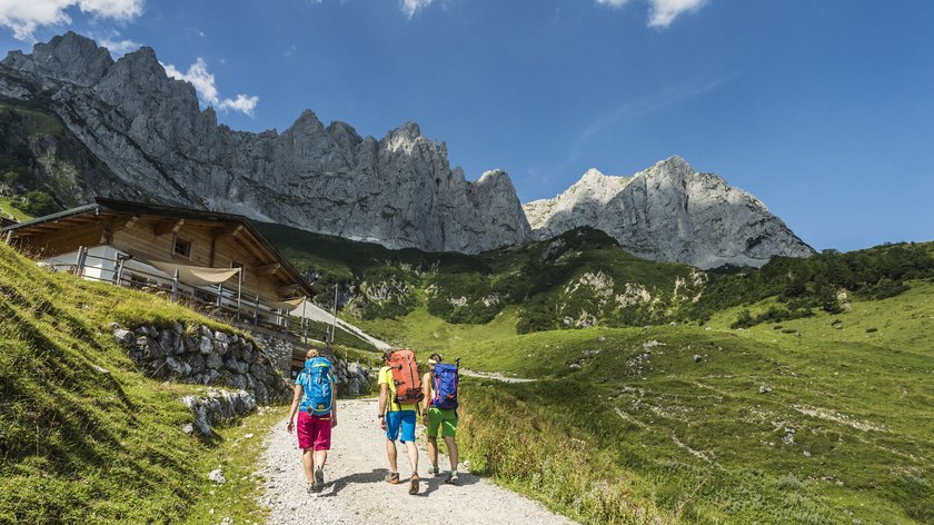 Wanderweg rund um den Achleitberg Drei Wanderer auf Bergweg mit Hütte und Felsen im Hintergrund