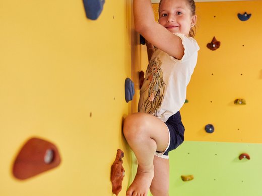 Family equipment at our family-friendly hotel in Soll. Child climbing a colorful indoor climbing wall with handholds