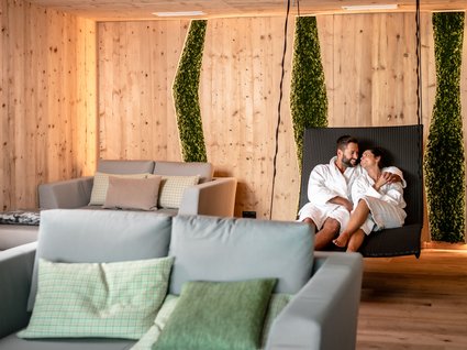 Day Spa in Söll: Kurzurlaub in Tirol Paar in Bademänteln entspannt auf Liege in modernem Holz- und Moos-Spa-Raum